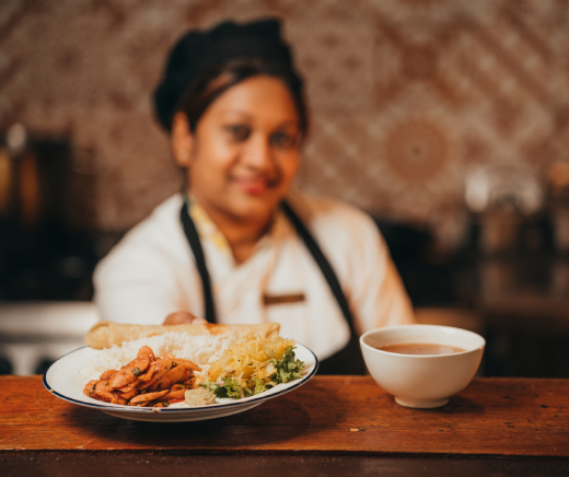 A woman presents a plate of Mauritian food, highlighting the rich flavors and cultural heritage of Mauritius.