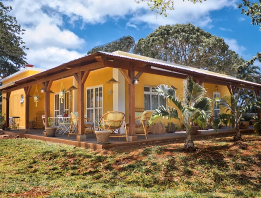 A bright yellow house with a covered porch and patio, representing a welcoming guest house in Mauritius.