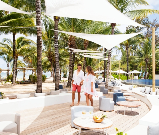 A couple walks on Bel Ombre C-Beach in Mauritius, with a splendid backdrop.