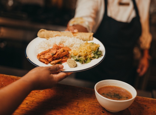 A person displaying a plate of Mauritius Creole food, featuring an assortment of traditional and flavorful dishes.